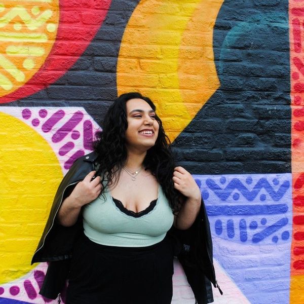 Ava Dudani smiling in front of a colorful mural