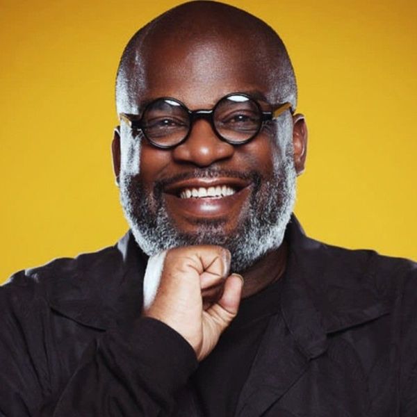 Headshot of a brightly smiling George (Chip) Greenidge, in front of a bright yellow wall