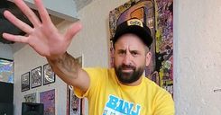 Chris Faraone waving at the camera in front of wall art